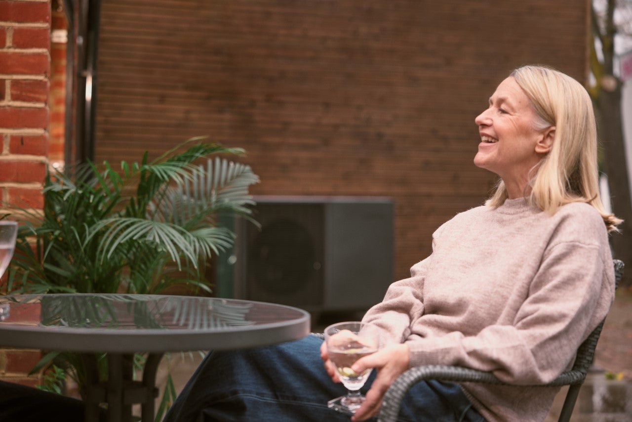 Woman enjoying a drink next to heat pump
